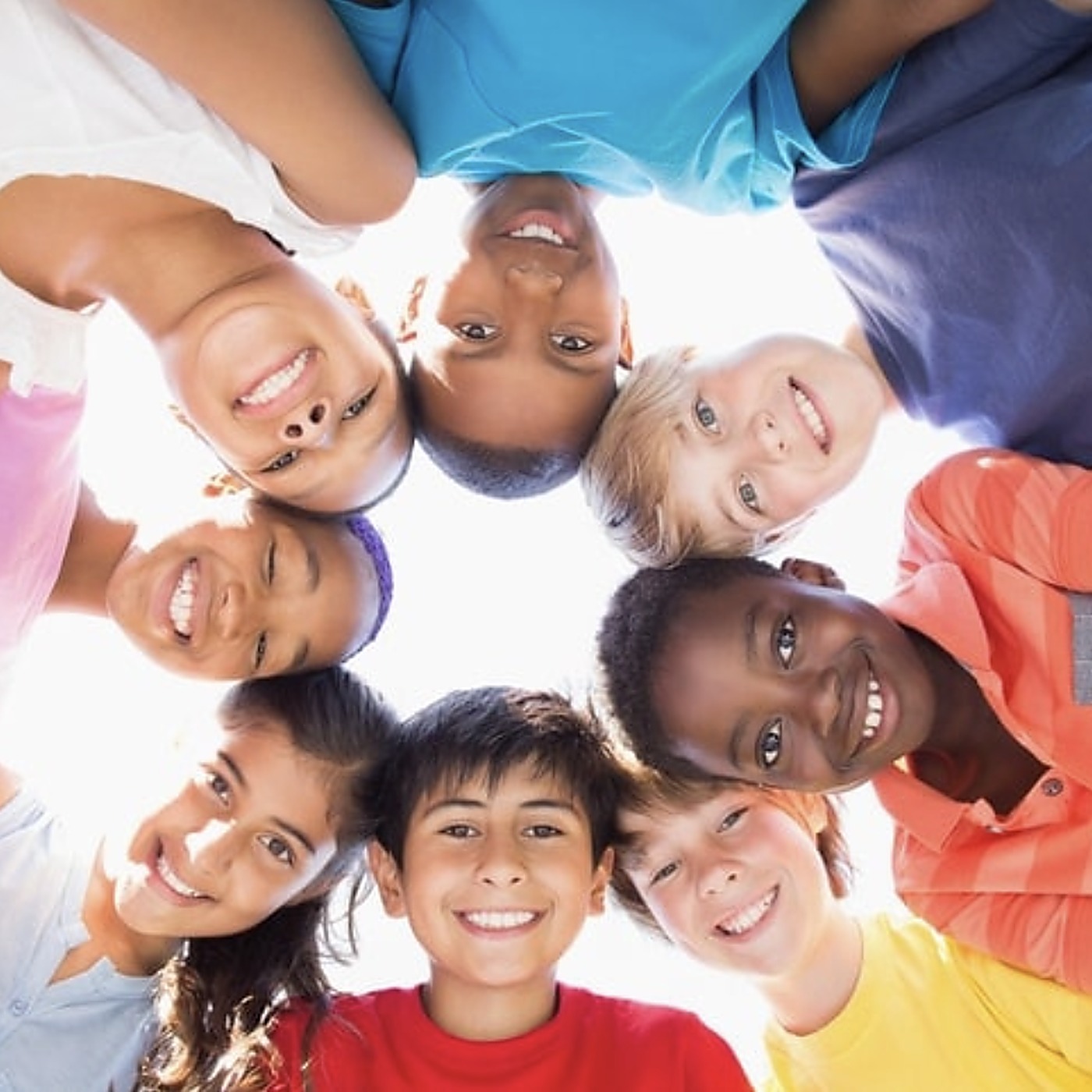 A joyful, multicultural circle of children smiling up at the camera